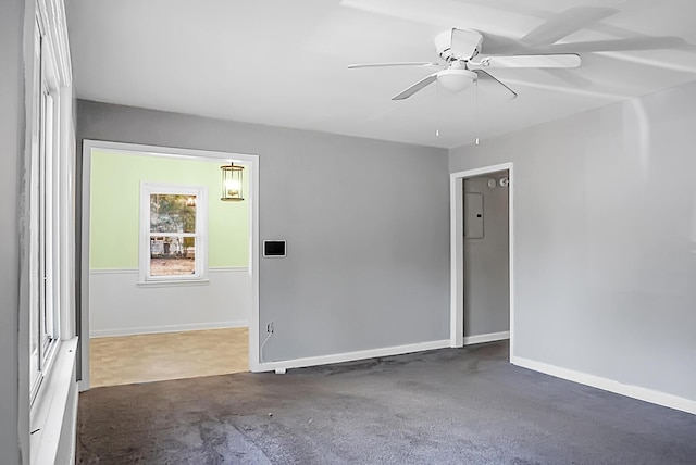 empty room with ceiling fan and dark colored carpet