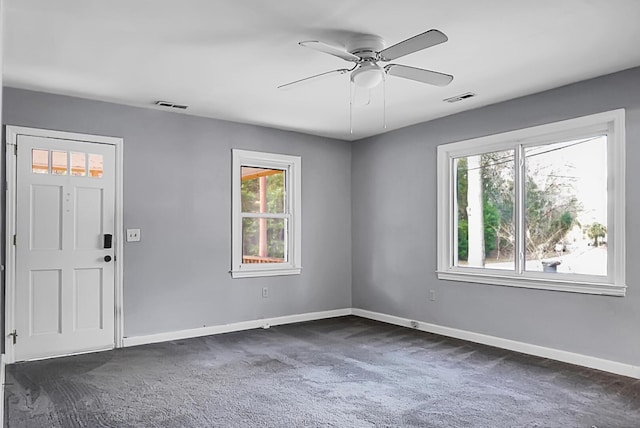 foyer featuring dark colored carpet, a healthy amount of sunlight, and ceiling fan