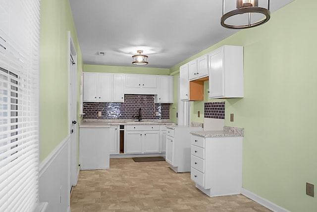 kitchen with tasteful backsplash, sink, and white cabinets