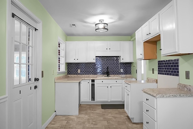 kitchen with sink, backsplash, and white cabinets