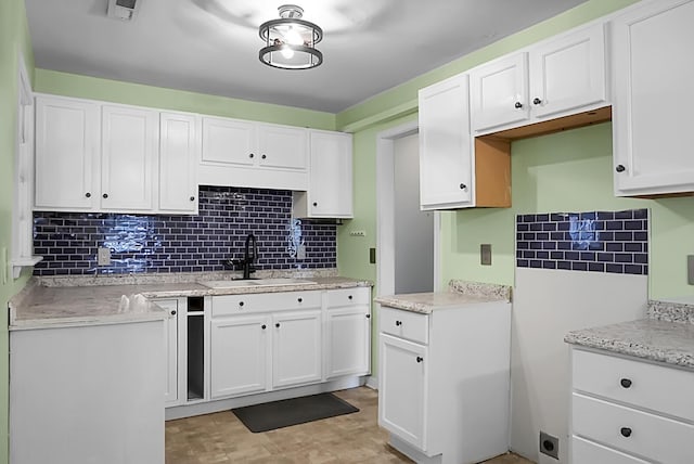 kitchen with white cabinetry, sink, tasteful backsplash, and light stone countertops