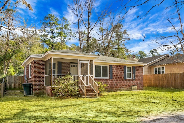 ranch-style home featuring a front lawn and a sunroom