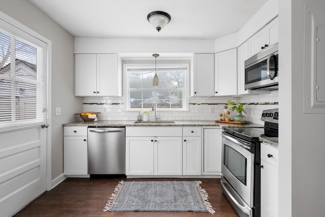 kitchen featuring appliances with stainless steel finishes, sink, white cabinetry, and hanging light fixtures