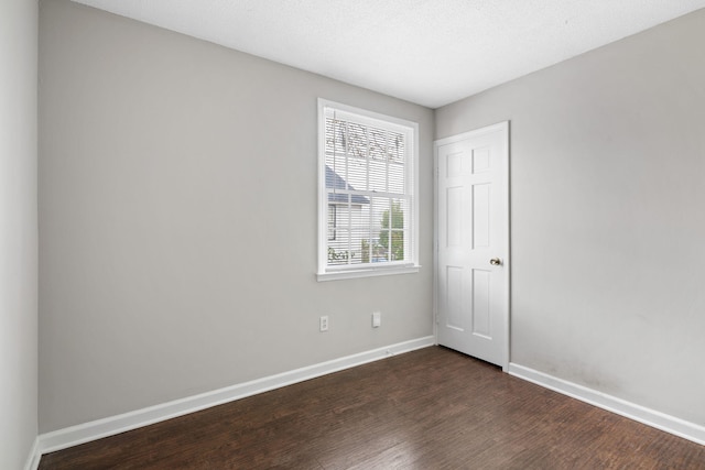 spare room with a textured ceiling and dark hardwood / wood-style floors