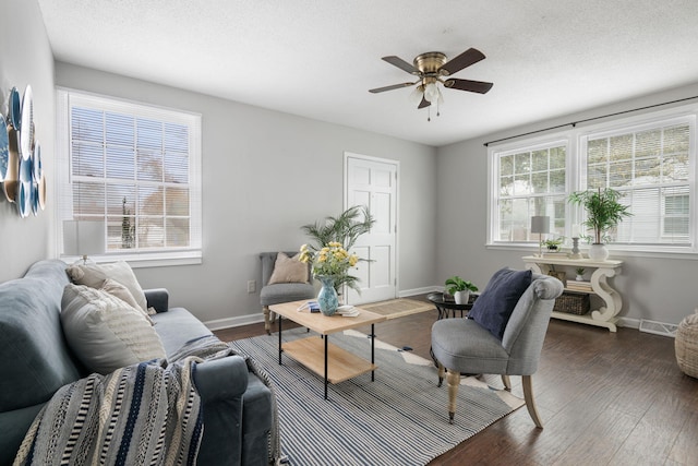 living room featuring ceiling fan, dark hardwood / wood-style flooring, and a textured ceiling