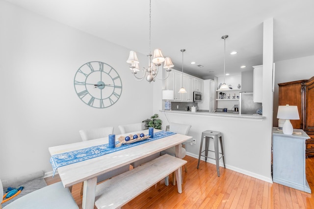 dining space featuring baseboards, light wood-style floors, recessed lighting, and a chandelier