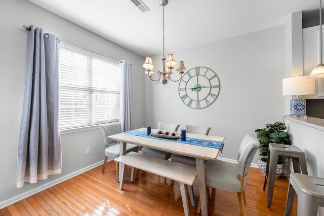 dining space with an inviting chandelier, light wood-style flooring, baseboards, and visible vents