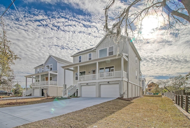 coastal home featuring board and batten siding, stairway, an attached garage, concrete driveway, and covered porch