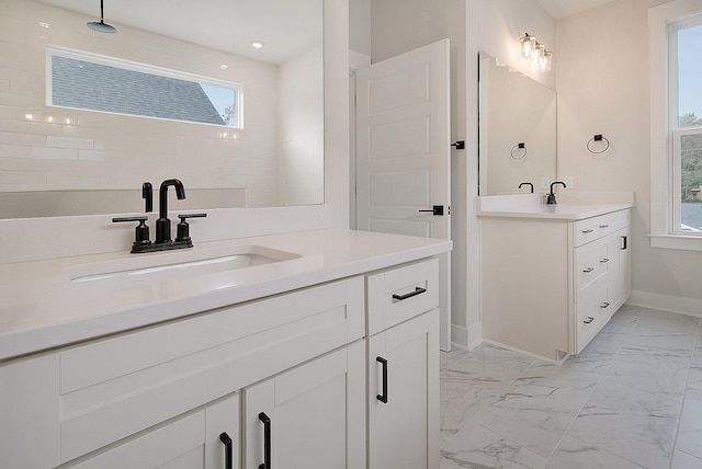 full bathroom with marble look tiles, baseboards, two vanities, and plenty of natural light