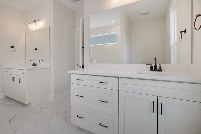 bathroom featuring two vanities, marble look tile flooring, baseboards, and recessed lighting