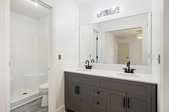 bathroom featuring wood-type flooring, toilet, vanity, and walk in shower