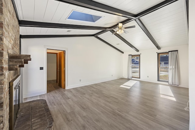 unfurnished living room featuring ceiling fan, a brick fireplace, hardwood / wood-style floors, and lofted ceiling with beams