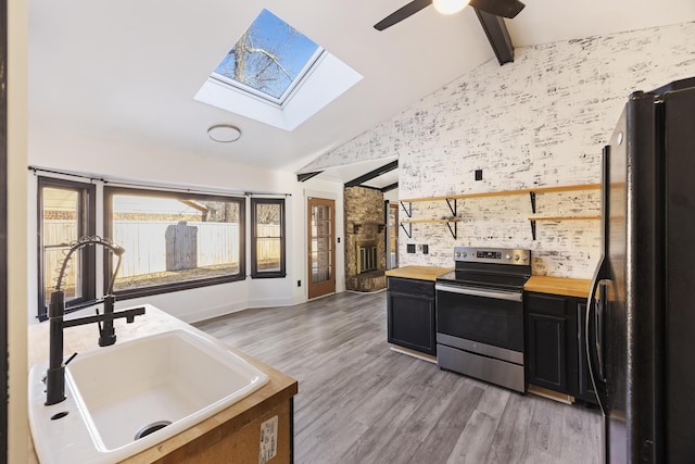 kitchen featuring black refrigerator, stainless steel electric range oven, hardwood / wood-style flooring, lofted ceiling with beams, and butcher block counters