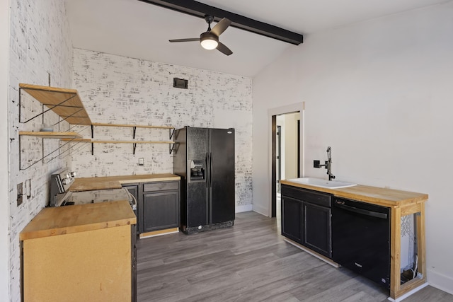 kitchen with sink, beam ceiling, butcher block countertops, hardwood / wood-style floors, and black appliances