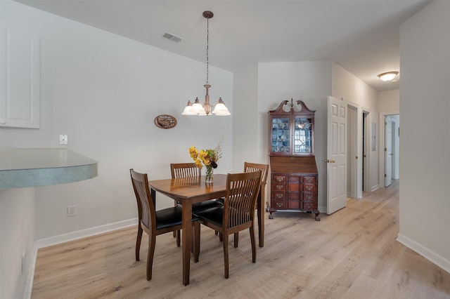 dining area featuring light hardwood / wood-style flooring and a notable chandelier