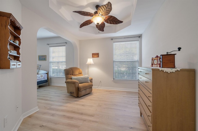 sitting room featuring a tray ceiling, light hardwood / wood-style floors, and ceiling fan