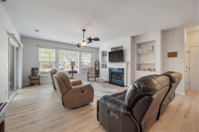 living room with light hardwood / wood-style flooring, built in shelves, and ceiling fan