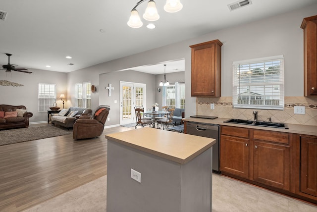 kitchen featuring visible vents, decorative backsplash, a sink, light countertops, and dishwashing machine