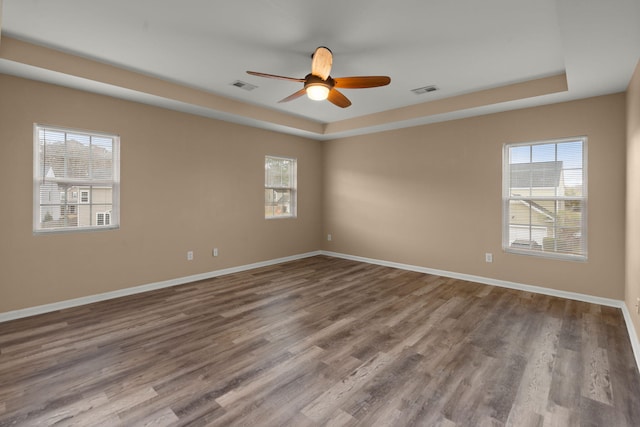 spare room with a raised ceiling, visible vents, and a wealth of natural light