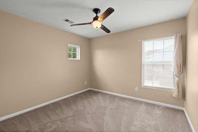 carpeted spare room with visible vents, a ceiling fan, and baseboards