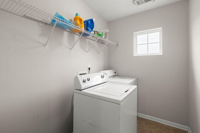 clothes washing area with baseboards, visible vents, washing machine and clothes dryer, laundry area, and dark tile patterned floors