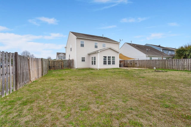 back of house featuring a fenced backyard and a yard