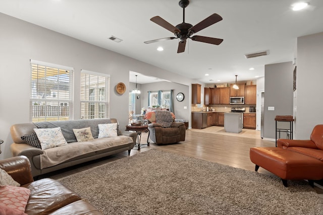 living room featuring light wood-style flooring, recessed lighting, visible vents, and ceiling fan