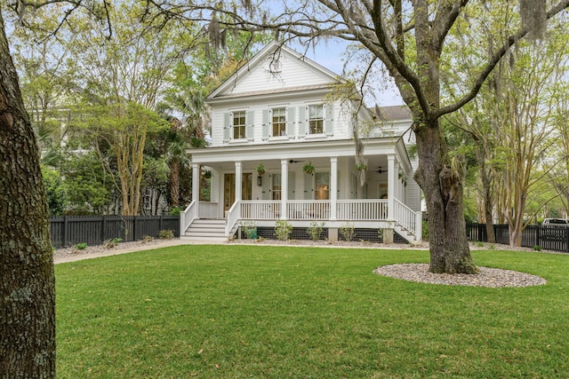 greek revival house with ceiling fan, a front yard, and covered porch