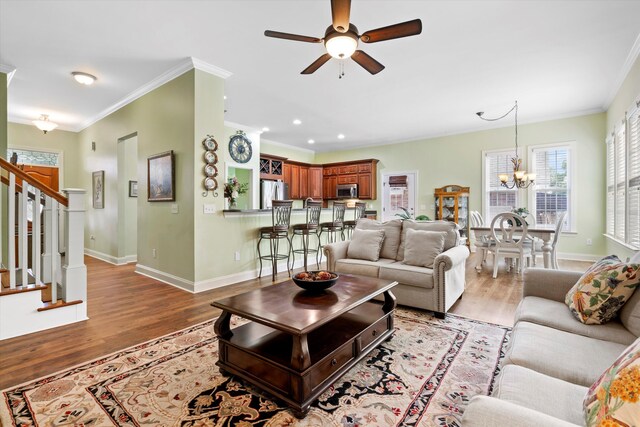 1119 Bruton Blvd, Moncks Corner, SC 29461 - living room with stairway, ceiling fan, a chandelier, crown molding, and light wood-style flooring