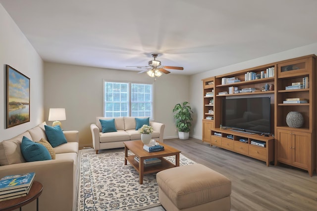 living room with light wood finished floors, a ceiling fan, and baseboards