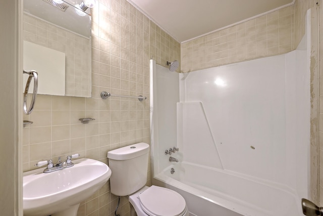 full bathroom featuring tile walls, washtub / shower combination, a sink, toilet, and tasteful backsplash