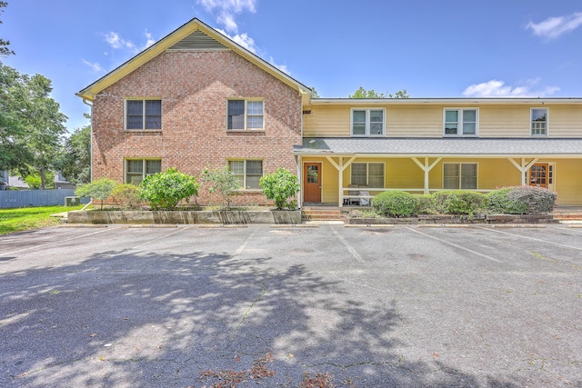 view of front of home featuring uncovered parking, brick siding, and covered porch