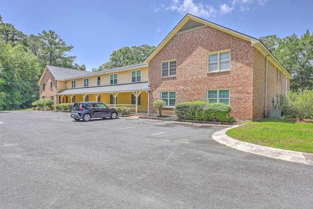 view of property with uncovered parking and cooling unit
