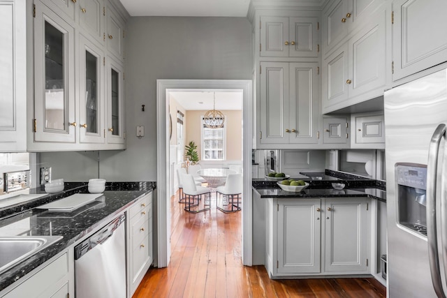 kitchen featuring decorative light fixtures, white cabinetry, light wood-type flooring, and stainless steel appliances