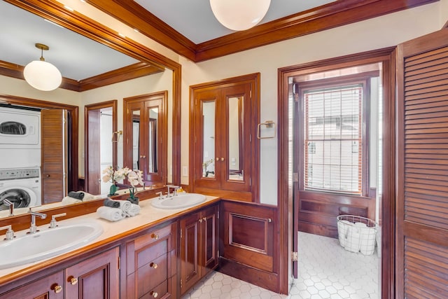 bathroom with tile patterned flooring, vanity, ornamental molding, and stacked washer and clothes dryer