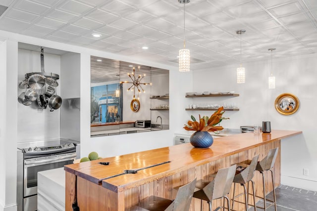 bar featuring dark tile patterned floors, hanging light fixtures, and stainless steel range with electric stovetop