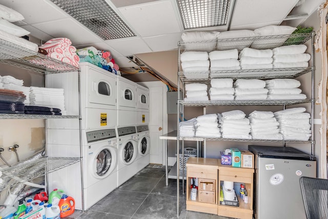 washroom with stacked washer and dryer and dark tile patterned floors