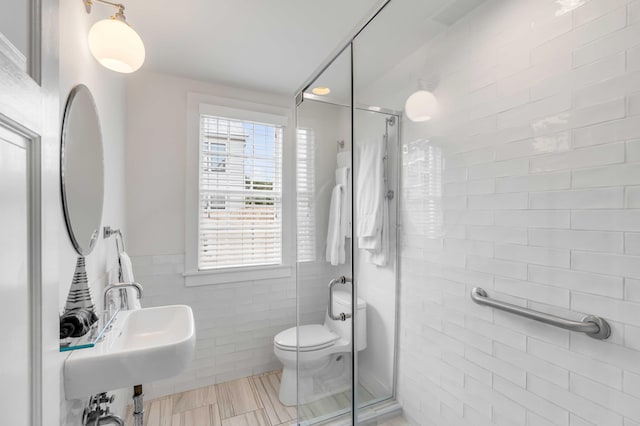 bathroom with tile patterned floors, walk in shower, sink, tile walls, and toilet