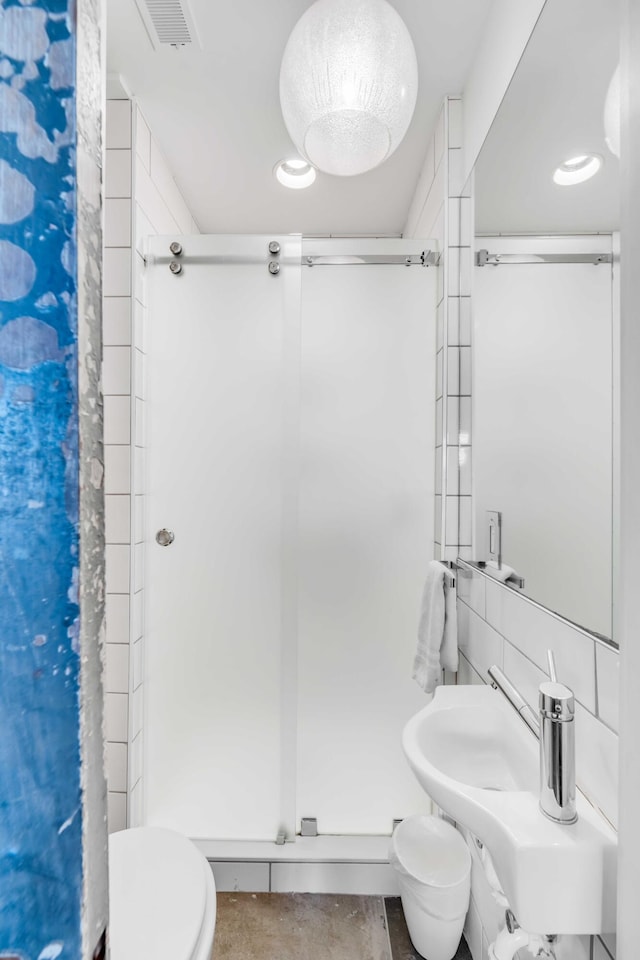 bathroom featuring tasteful backsplash, toilet, a shower with door, and tile walls