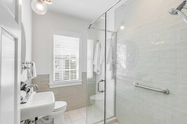 bathroom with tile patterned floors, walk in shower, sink, tile walls, and toilet