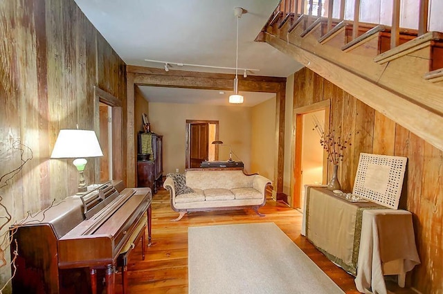 sitting room with stairway, wooden walls, wood finished floors, attic access, and track lighting