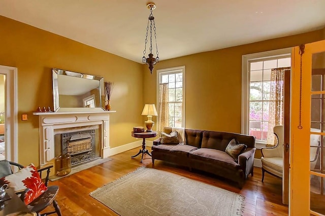 living area with baseboards, a fireplace with flush hearth, and wood finished floors