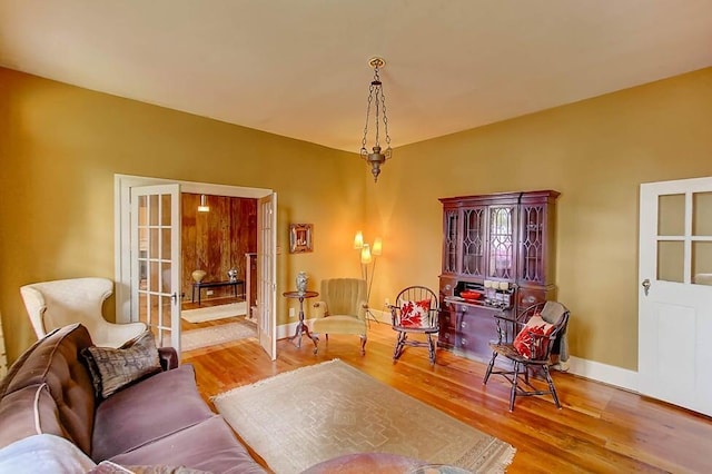 living area featuring wood finished floors, baseboards, and french doors