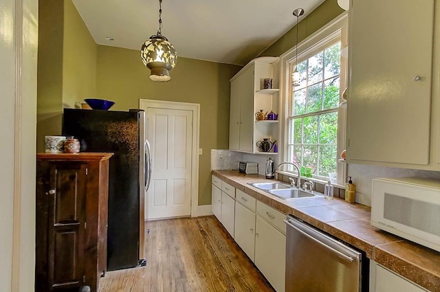 kitchen featuring light wood-style flooring, a sink, appliances with stainless steel finishes, white cabinets, and tile counters