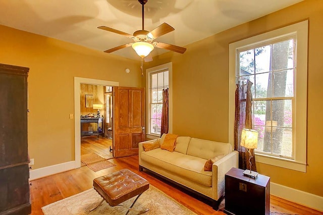 living area with wood finished floors, baseboards, and ceiling fan