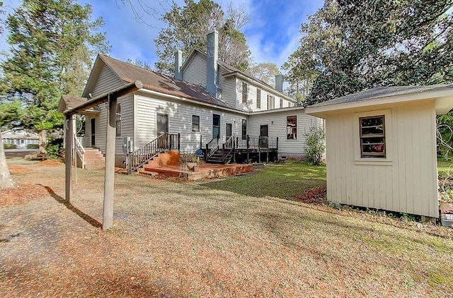 rear view of house featuring a chimney, an outdoor structure, and a yard