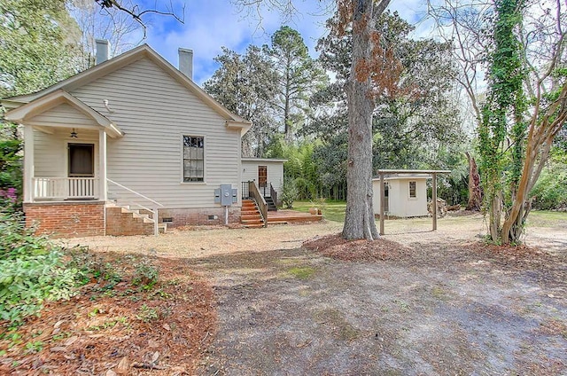back of property with crawl space, a chimney, and an outbuilding
