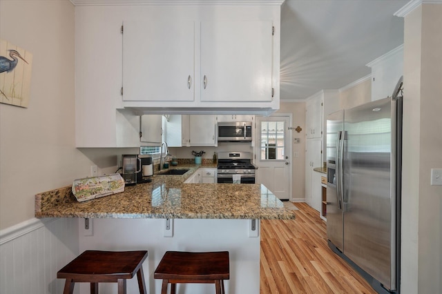 2220 Pinehurst Ave, Charleston, SC 29414 - kitchen featuring stainless steel appliances, a sink, a peninsula, light wood-style flooring, and white cabinetry