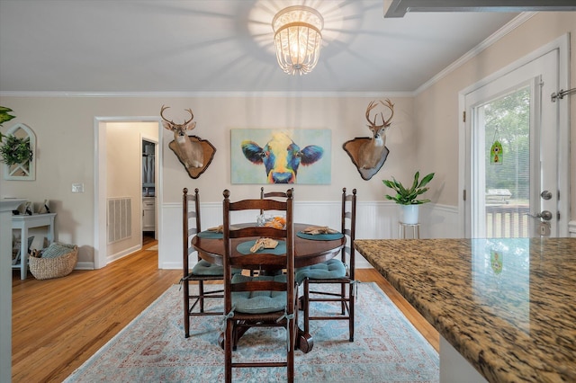 2220 Pinehurst Ave, Charleston, SC 29414 - dining space with light wood-style flooring, crown molding, a chandelier, and a wainscoted wall