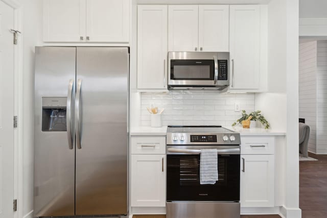 kitchen featuring white cabinetry, backsplash, wood-type flooring, and appliances with stainless steel finishes